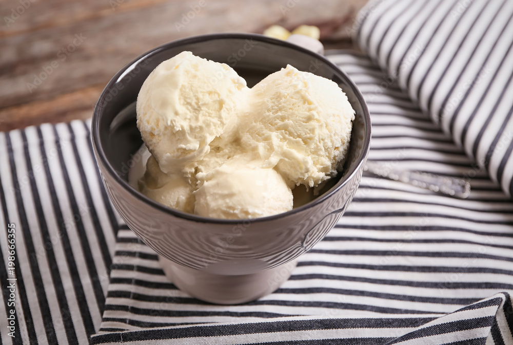 Cup with delicious vanilla ice cream on table