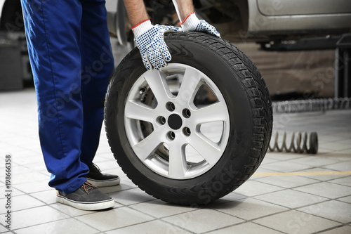 Mechanic with car tire in service center, closeup © New Africa