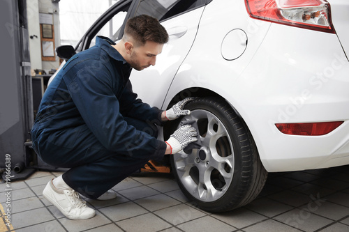 Young mechanic cleaning wheel at tire service