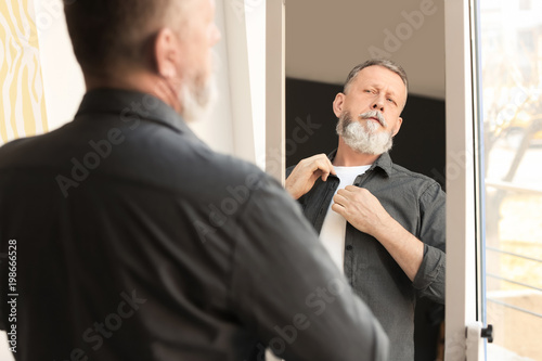 Mature man looking in mirror at home