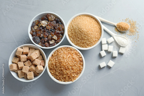 Flat lay composition with different types of sugar on gray background