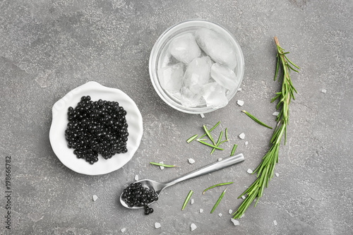 Black caviar served with ice on grey background