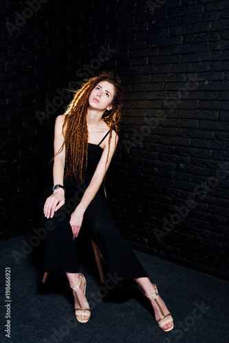 Studio shoot of girl in black on chair with dreads on brick background. © AS Photo Family