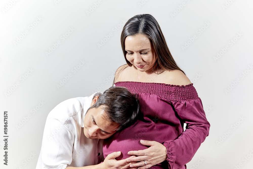 Young Man resting his ear against a Pregnant Woman's Belly Young Man resting his ear against a Pregnant Woman's Belly