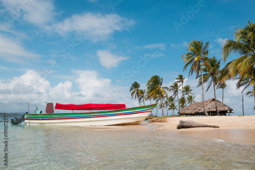 boat on island beach with palm tree and bungalow background - San Blas Islands, photo