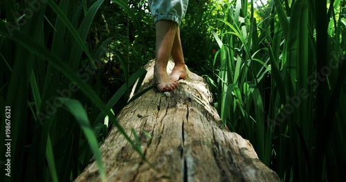 Woman walking over a wooden log in the park photo