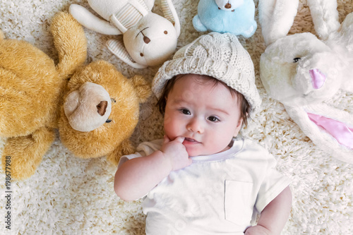 Baby boy with his stuffed animals on a white carpet