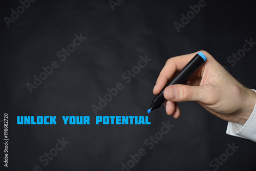 The businessman writes a blue marker inscription:UNLOCK YOUR POTENTIAL