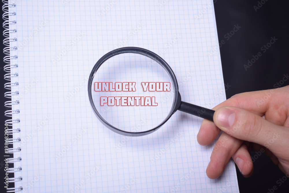 Businessman looking at a magnifying glass word:UNLOCK YOUR POTENTIAL Businessman looking at a magnifying glass word:UNLOCK YOUR POTENTIAL