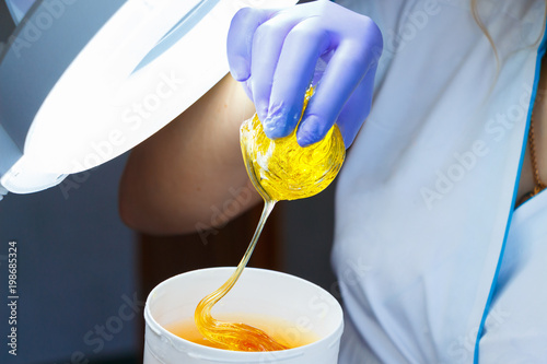 Woman holding sugar hair removing paste in hand. Depilation concept. Close up.