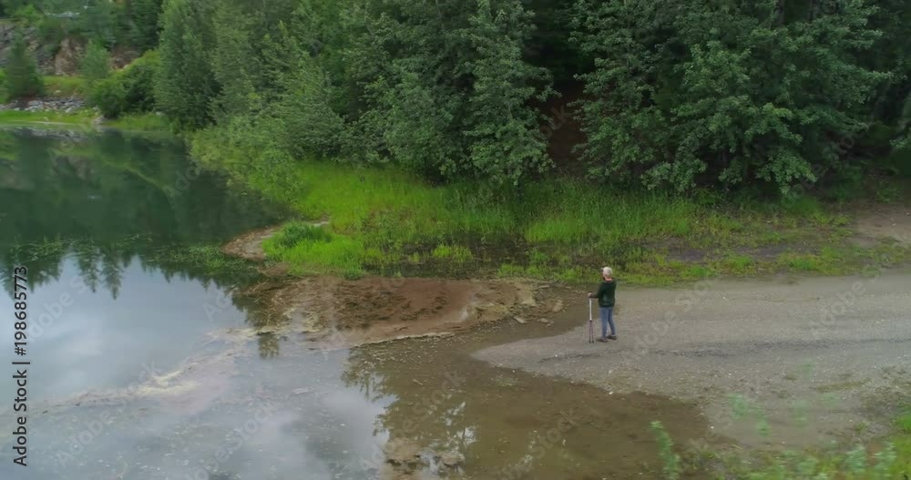 Aerial view of mature woman standing near a lake Aerial view of mature woman standing near a lake