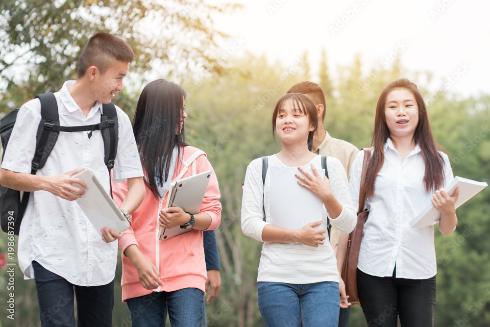 Education learning Concept: Confident Asian Students groups walking hold books, tablet notebook at Outside classroom in university with happy. Education learning Concept: Confident Asian Students groups walking hold books, tablet notebook at Outside classroom in university with happy.