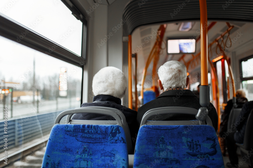 Senior couple travelling on the bus. There are other people sat on the bus who are in the background Senior couple travelling on the bus. There are other people sat on the bus who are in the background