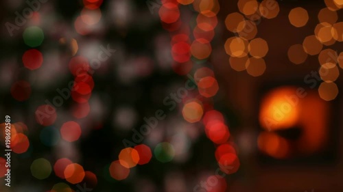 Christmas gifts in front of fireplace and blurry lights on xmas tree in the evening - camera zooming out and focusing on foreground