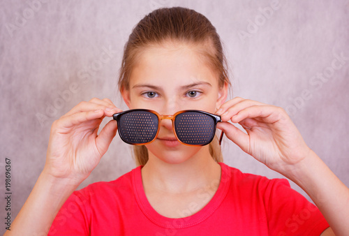 Obraz na płótnie The girl is preparing to try on training glasses for vision correction w salonie