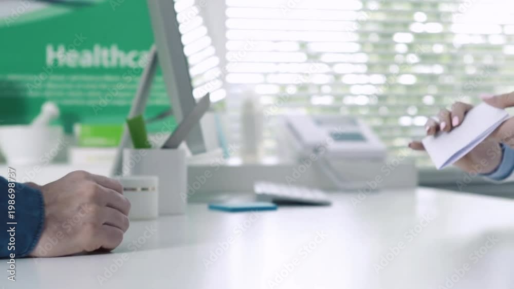 Customer giving a prescription to a pharmacist Customer giving a prescription to a pharmacist