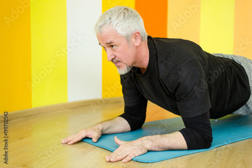 Adult male trains in the gym against a yellow wall © pantovich