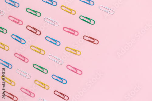 Paper clips in different colors against rose background minimalistic flat lay concept. © zphoto83