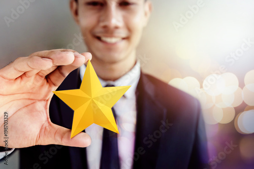 Success in Business or Personal Talent Concept. Happy Businessman in black suit Smiling and Showing a Golden Star in Hand photo