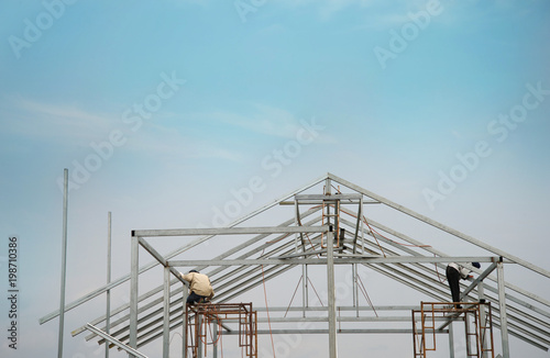 workers on metal structure home building construction industry with blue sky background
