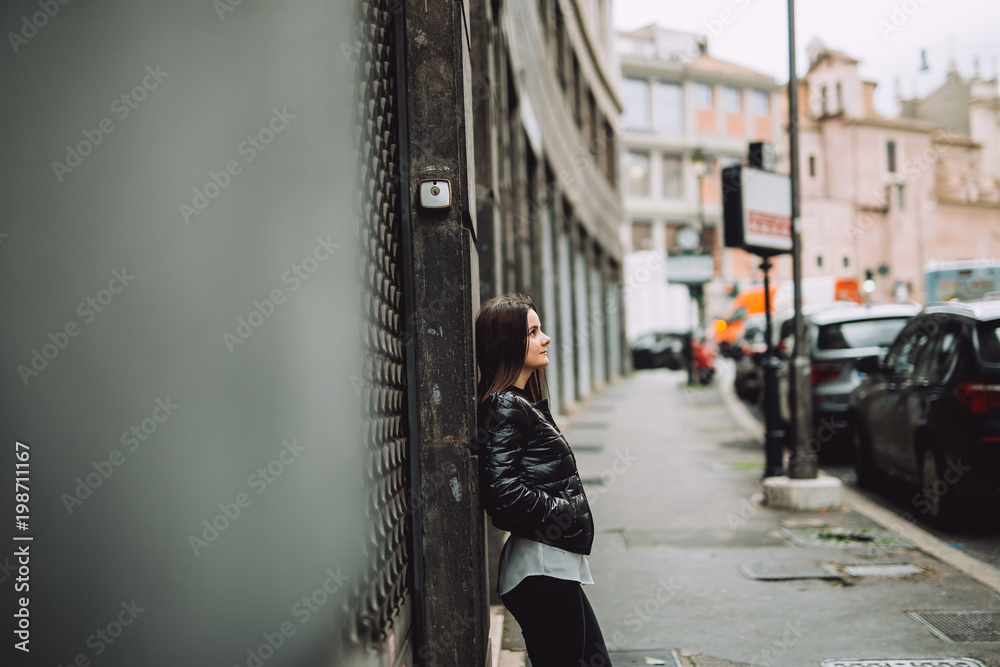 Young girl leaning against the wall in the city