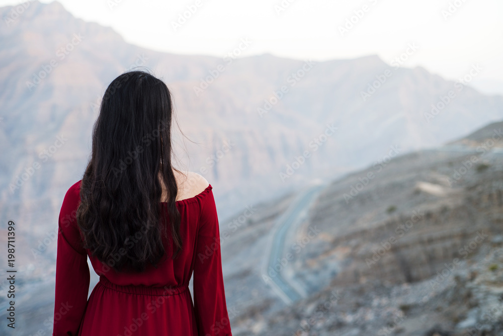 Woman in red dress on a desert mountain top
