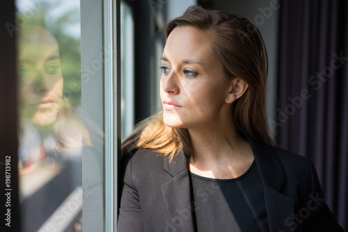 Quadro su tela Closeup portrait of pensive young beautiful brown-haired woman looking through window