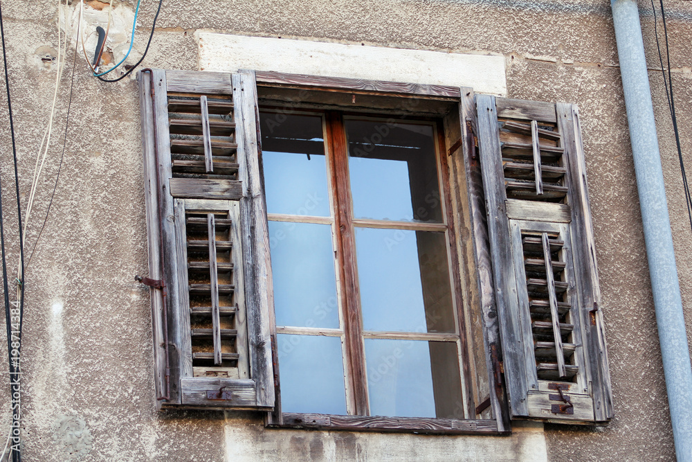Old window with rotten and cover wooden shutters of historical building in Pula, Croatia, closeup / Building facade elements, material, texture, background and wallpaper / Architecture urban concept.
