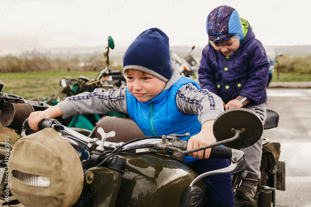 two boys sitting on an old three-wheeled motorcycle two boys sitting on an old three-wheeled motorcycle