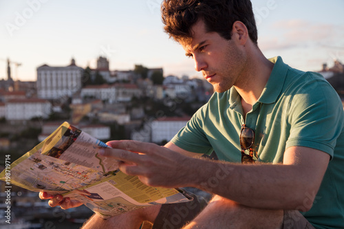 Man on vacation looking at tourist map during sunset photo