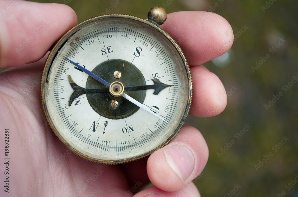 Traveler holding compass in hand. Compass in a hand blurred background Traveler holding compass in hand. Compass in a hand blurred background