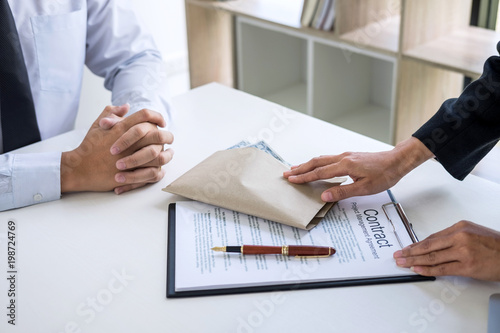 Bribery and corruption concept, bribe in the form of dollar bills, Businessman giving money in the envelope while making deal to agreement a real estate contract and financial corporate