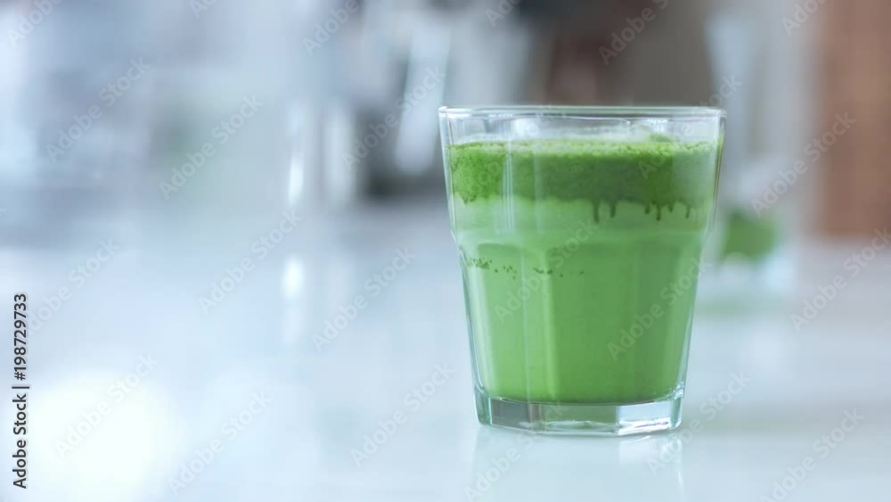 male hand puts a glas with matcha late on bar table