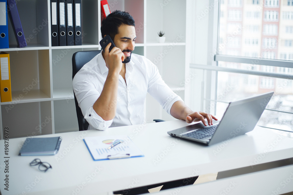 Smiling businessman using laptop at desk in office Smiling businessman using laptop at desk in office