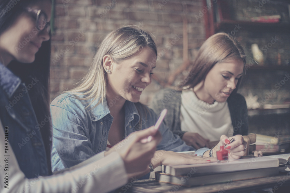 Three girls students. Two girls lacquer nails. Focus on background. Three girls students. Two girls lacquer nails. Focus on background.