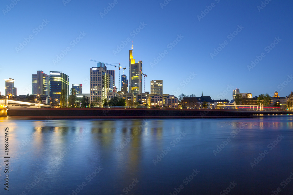 Bankenviertel von Frankfurt in der Abenddämmerung mit vorbeifahrendem Schiff