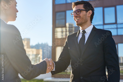 Successful agent or broker greeting his client by handshake after signing contract photo