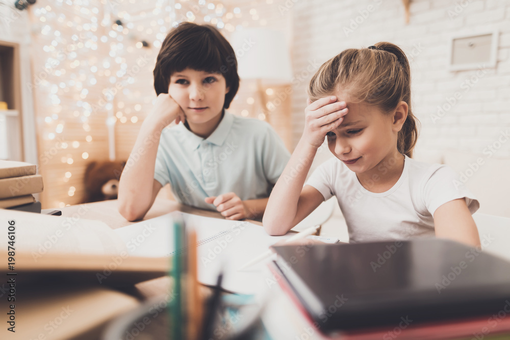 Children at home. Brother and sister are doing homework, writing in notebook. Children at home. Brother and sister are doing homework, writing in notebook.