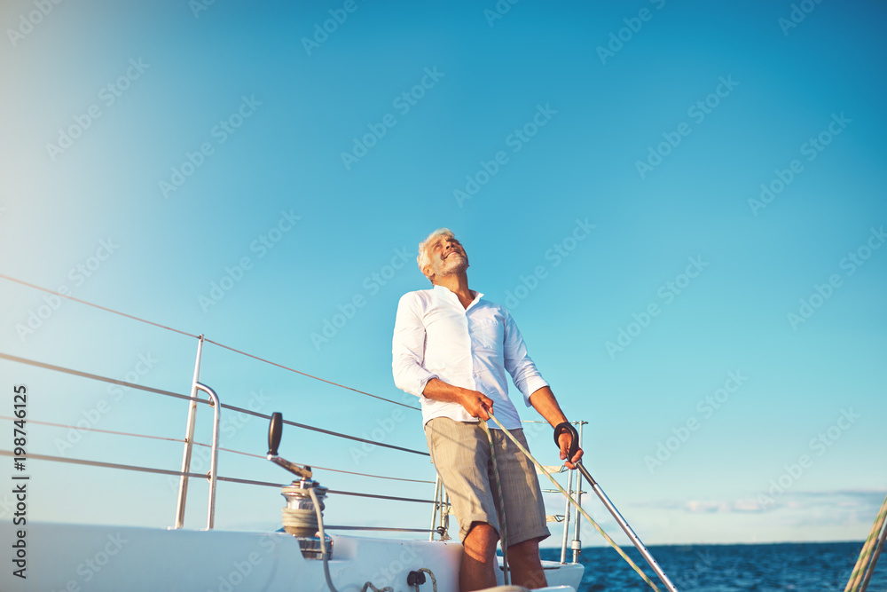 Mature man looking skyward while out sailing on his boat Mature man looking skyward while out sailing on his boat