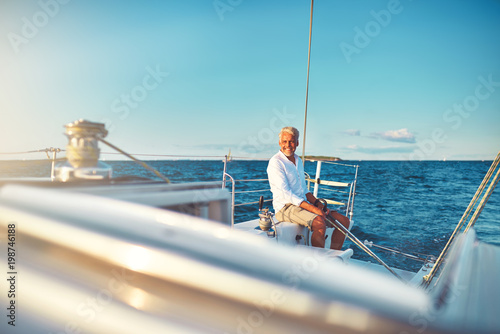 Smiling mature man sailing his yacht at sea