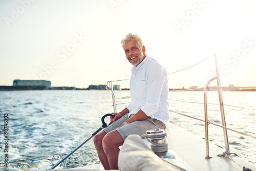 Smiling mature man sailing his boat along the coast