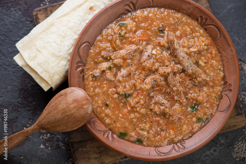 Tableau sur toile Clay plate of traditional georgian soup kharcho with lavash, view from above