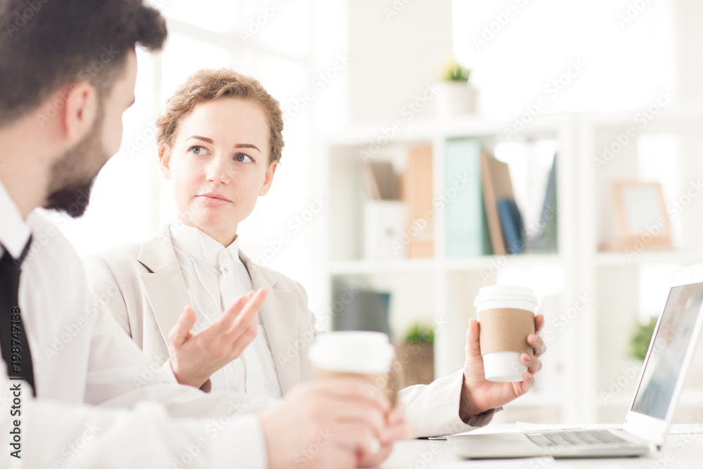 Two coworkers planning work and drinking coffee Two coworkers planning work and drinking coffee