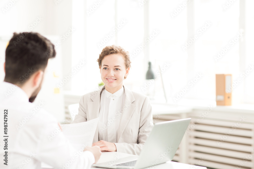 Smiling businesswoman communicating with her colleague at the table at office Smiling businesswoman communicating with her colleague at the table at office
