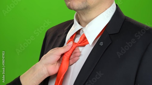 Woman's hand adjusts the tie around her servant's neck. Green screen. Close up photo