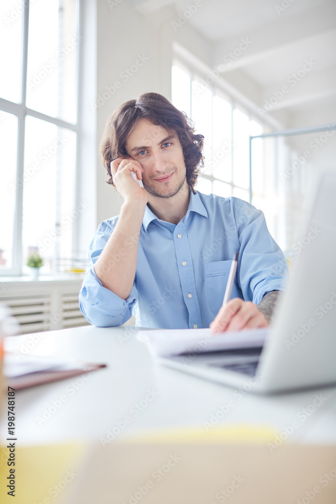 Portrait of businessman having a conversation on the phone and making notes at the table Portrait of businessman having a conversation on the phone and making notes at the table