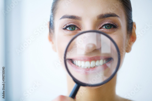 Funny woman smiling and show teeth through a magnifying glass