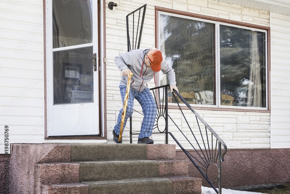 elderly man exiting his home down the steps with cane