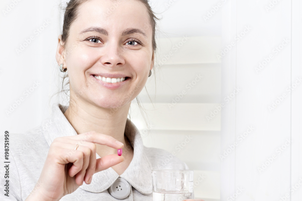 Young attractive woman holds in her hand pill and glass of clean water. Girl takes pills. Healthcare concept. Healthy life. girl is treated with pills. Medicine at home. Take vitamins in tablets Young attractive woman holds in her hand pill and glass of clean water. Girl takes pills. Healthcare concept. Healthy life. girl is treated with pills. Medicine at home. Take vitamins in tablets