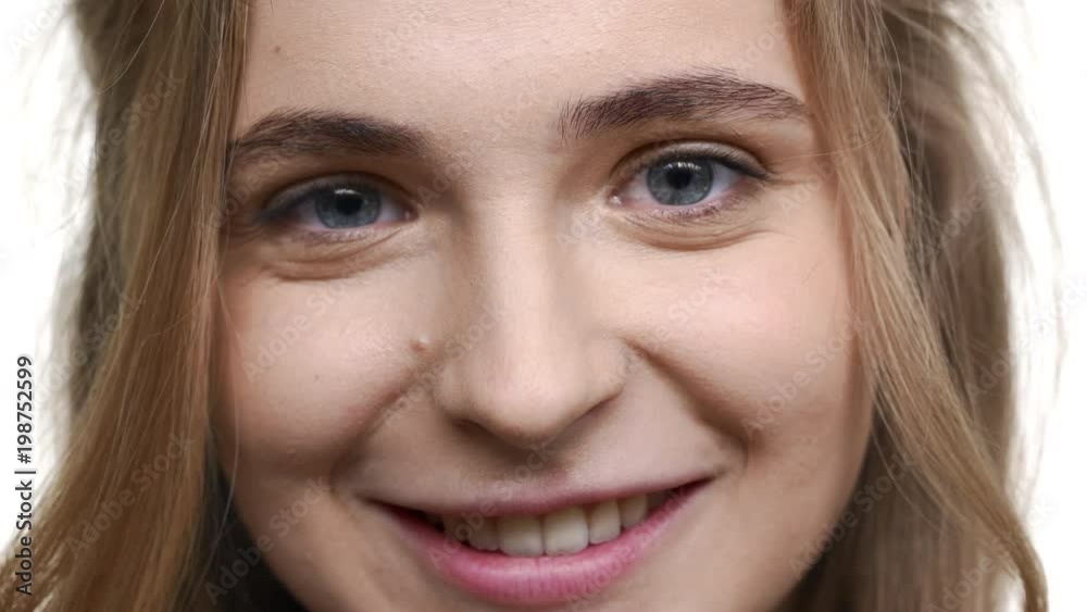 Extreme closeup portrait of beautiful young woman 20s with curly brown hair expressing optimism with candid look and smile, isolated over white background. Concept of emotions Extreme closeup portrait of beautiful young woman 20s with curly brown hair expressing optimism with candid look and smile, isolated over white background. Concept of emotions